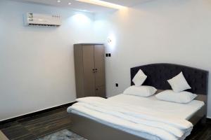 Schlafzimmer mit einem Bett mit weißer Bettwäsche und Kissen in der Unterkunft نيلوفر بيتي in Sūq al Aḩad