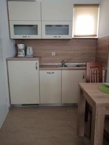 een keuken met witte kasten, een wastafel en een tafel bij Apartman Branka in Rab