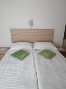 een groot wit bed met twee groene kussens erop bij Apartman Branka in Rab