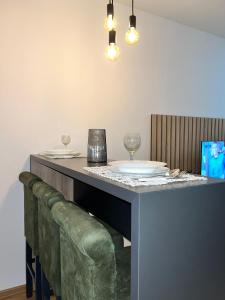 a bar with a green couch under a table with glasses at Apartmani Profesional Pajkovic in Valjevo