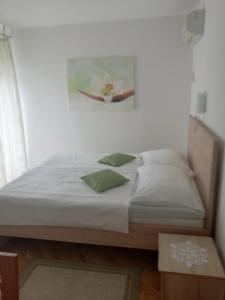 een bed met witte lakens en groene kussens in een kamer bij Apartman Branka in Rab