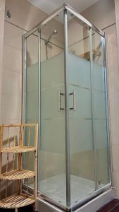una cabina de ducha de cristal en una habitación con silla en Hospedería Nieves Centro, en Chipiona