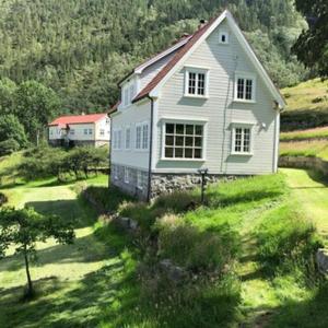 ein weißes Haus auf einem grasbewachsenen Hügel mit einem Haus in der Unterkunft Flørli 4444 Lysefjorden - Director's residence in Sandnes