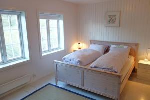 ein Schlafzimmer mit einem Bett mit zwei Kissen und zwei Fenstern in der Unterkunft Flørli 4444 Lysefjorden - Director's residence in Sandnes