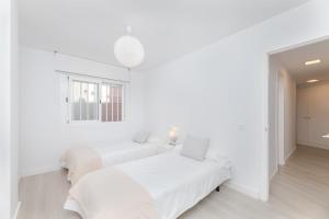 - 2 lits dans une chambre aux murs blancs dans l'établissement Barquilla Apartment - Kura Homes, à Marbella