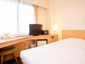 a hotel room with a bed and a desk with a television at le Lac Hotel Yokkaichi in Yokkaichi