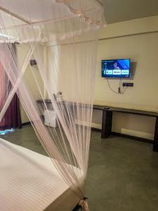 ein Schlafzimmer mit einem Bett mit einem Vorhang und einem TV in der Unterkunft Lankapura Heritage in Sigiriya