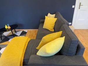 un divano grigio con cuscini gialli in soggiorno di Stadtoase Berlin nähe Olympiastadion a Berlino