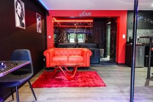 an orange couch in a room with a red wall at Love Room Passion in Saint-Hilaire-de-Talmont