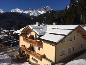 a house covered in snow with mountains in the background at Appartamento da Meto in San Martino di Castrozza