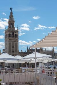 een groot gebouw met een klokkentoren en witte parasols bij Hotel Convento La Gloria in Sevilla