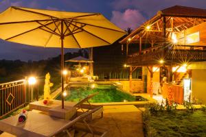 a patio with an umbrella and a pool at night at The Pyramid Ubud River Villas in Gianyar