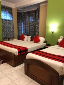 two beds in a room with green walls and red pillows at HOTEL BREEZE NEW JALPAIGURI in Siliguri