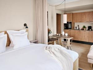 a bedroom with a white bed and a kitchen at Aura Apartment Hotel in Aarhus