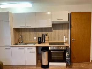 a kitchen with white cabinets and a sink and a stove at Ferienwohnung Haus am Bach in Toggenburg in Wildhaus