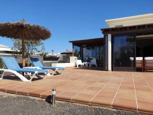 eine Terrasse mit 2 Stühlen und einem Sonnenschirm in der Unterkunft Villa La Carabela 35 in Playa Blanca