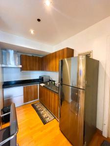 a kitchen with a stainless steel refrigerator and wooden cabinets at Luxury 2BR Penthouse in Gramercy, Makati in Manila