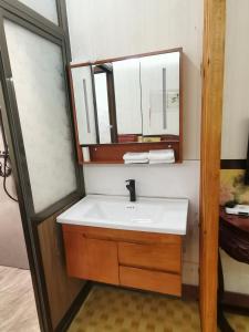 ein Bad mit einem Waschbecken und einem Spiegel in der Unterkunft Pingyao Yan Family Homestay in Pingyao