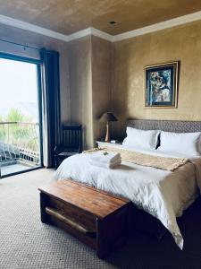 een slaapkamer met een groot bed, een tafel en een raam bij Beachfront House in Groot Brak Rivier