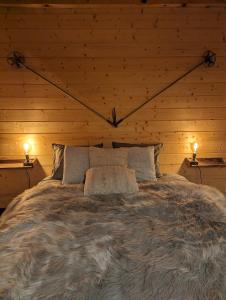 Cama en habitación de madera con 2 lámparas en Chalet Adler, en Saas-Fee