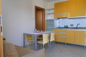 eine Küche mit einem Tisch und einigen gelben Schränken in der Unterkunft Lovely holiday home with fenced garden and pool in Bibione