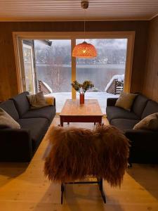 uma sala de estar com sofás e uma mesa com uma grande janela em Cabin by the Fjord em Øksendalsøra