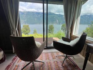 duas cadeiras sentadas em frente a uma grande janela em Cabin by the Fjord em Øksendalsøra