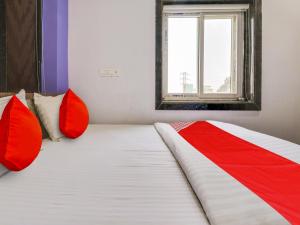 1 cama con almohadas rojas y blancas y ventana en OYO Flagship BABLU GRAND IN HOTEL en Hyderabad
