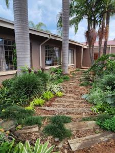 a walkway in front of a house with palm trees at Bendor Garden Flat in Polokwane