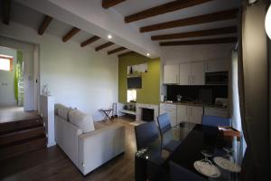 a living room with a white couch and a kitchen at Apartamentos Rurais - Casas do Lagar in Rosmaninhal