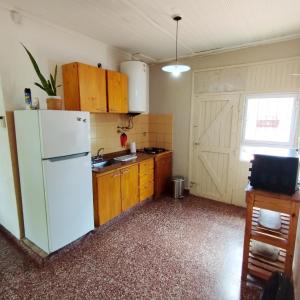 uma cozinha com um frigorífico branco e armários de madeira em Casa y monoambiente para 8 patio y 3 garaje - Tangará em Posadas