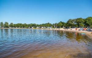 un gran cuerpo de agua con gente en una playa en Family friendly holiday home en Hulshorst