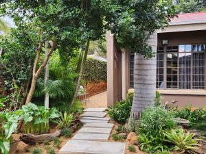 a garden with a walkway in front of a house at Bendor Garden Flat in Polokwane
