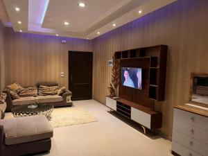 a living room with a couch and a tv at Cozy Apartmen with Garden in Sheikh Zayed in Sheikh Zayed