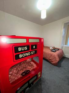 una maleta roja en una habitación con cama en Station Signature Apartment near Lanark, en Carstairs