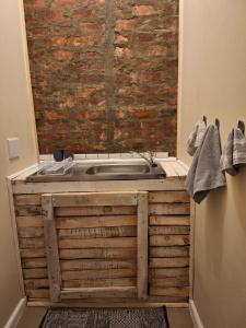 baño con bañera de madera y pared de ladrillo en Country Cottage, en Tulbagh