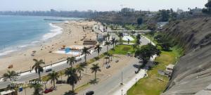 HOSPEDAJE TURISTICO CHORRILLOS Sueños de Luna INN في ليما: اطلالة جوية على شاطئ به نخيل والمحيط