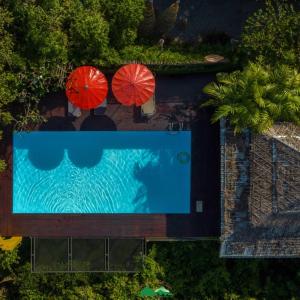 an overhead view of a swimming pool with two red umbrellas at Khao Sok Boutique Camping - Exotic Cliff Camping in Ban Bang Thong
