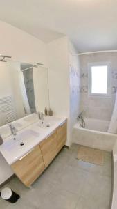 y baño con lavabo, bañera y espejo. en La Maison Vermeil - Grande maison moderne à Lavaur, en Lavaur