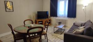 a living room with a table and a couch at Appartement 4 personnes, 2 ch, parking gratuit et facile in Montceau-les-Mines