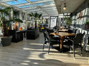un restaurante con mesa de madera, sillas, mesas y ventanas en Hotel Wochtla Buam, en Brunico