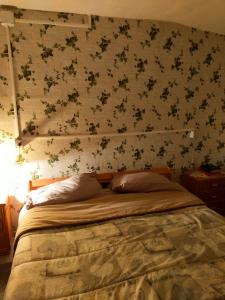 1 dormitorio con 1 cama con pared de flores en Monolocali Tra Rieti e Terminillo tra le nevi en Terminillo