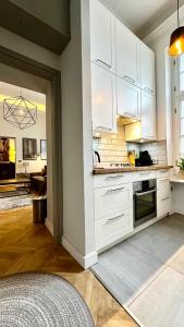 a kitchen with white cabinets and a living room at 4m high apartment in heart of Warsaw! in Warsaw