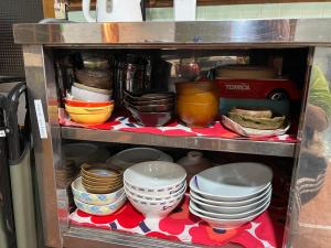 a shelf with plates and bowls and other dishes at Cozy and Cheap Kinosaki Hideya Non Japanese in Toyooka