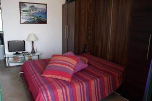 a bed with a striped blanket and a television at Cozy studio in Balchik in Balchik