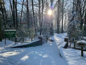 un parque cubierto de nieve con un cartel y árboles en Kokoon in 't groen, en Lovaina