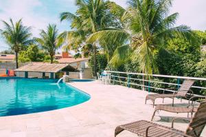 een zwembad van het resort met stoelen en palmbomen bij MB Pousada SOL in Conde