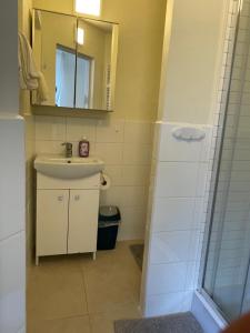 a bathroom with a sink and a shower with a mirror at Apartament Central Sopot in Sopot