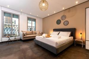 a bedroom with a bed and a couch and windows at Jaffa Port TLV Hotel Apartments יפו תל אביב in Tel Aviv