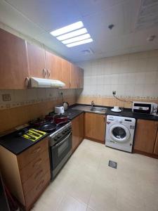 a kitchen with a stove and a washing machine at Cozy 1Bhk with stunning sea view in Sharjah